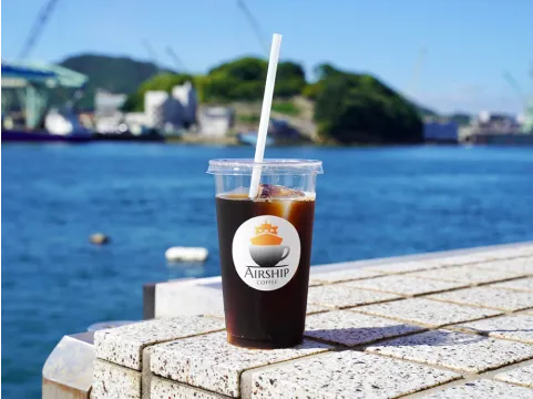 写真:海を背景にしたアイスコーヒー
